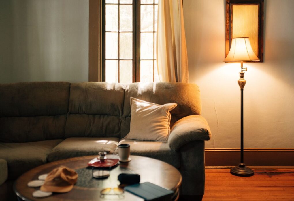 Warm, cozy living room with a glowing floor lamp beside a sofa, showing how warm tones offset cool north light