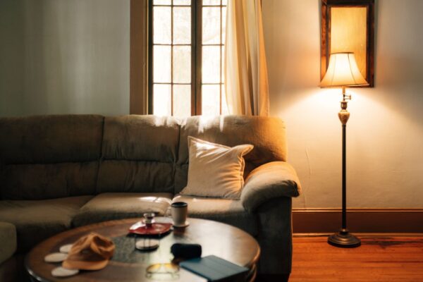 Warm, cozy living room with a glowing floor lamp beside a sofa, showing how warm tones offset cool north light