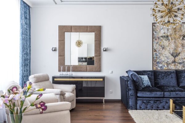 Luxurious rental apartment living room with a velvet sofa, oversized mirror, wall sconces and floor-length curtains